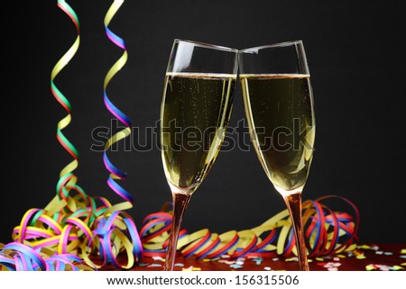 Celebrating with sparkling wine and colorful paper streamers, black background.