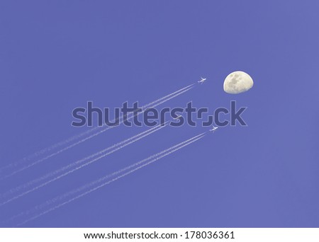Airplane condensation line on sky with moon