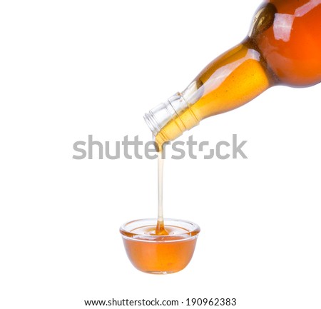 honey flow dropping from  glass  bottle to glass cup isolated on white