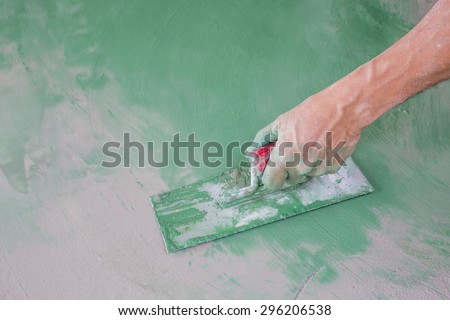 Workers hand plastering color combination a floor with trowel. Construction worker. Masonry tool. Construction industry. Selective focus.