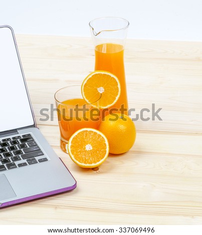 Laptop with orange  and  orange juice  in glass  on  wood  background