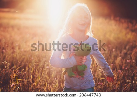 Happy Little Blonde Girl Playing in Summer Sunset Field
