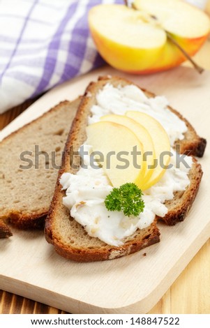 Bread with lard and apple slices on wooden board