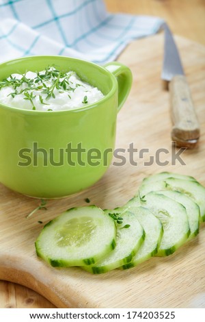 Cucumber slices with yogurt and garden cress on a wooden board