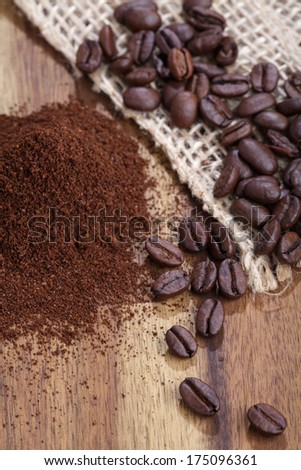 Coffee beans and ground coffee on wooden board