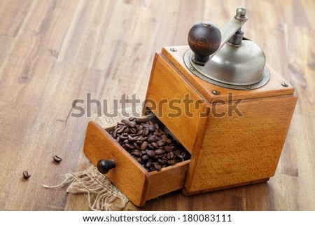 Nostalgic coffee grinder and coffee beans on wooden board
