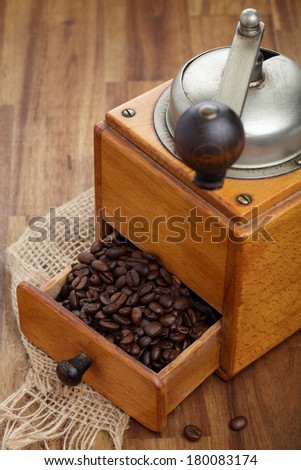 Nostalgic coffee grinder and coffee beans on wooden board