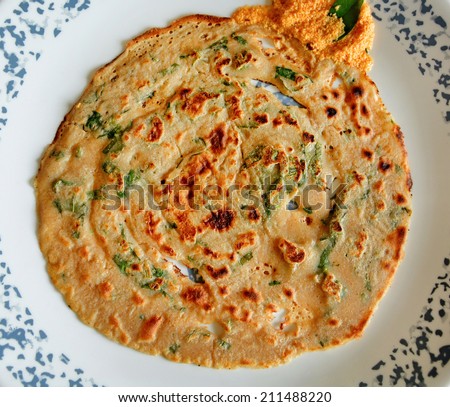 Kerala food. Nutritious, healthy, delicious vegetarian  South Indian breakfast. Wheat dosa, garnished with parsley leaves, and coconut chutney garnished with curry leaf on white plate. top view