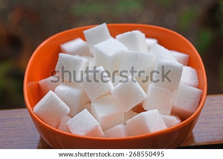 White poison. Rich in calories. The silent sweet killer of modern man - reason for obesity and diabetes. Sugar cubes in a plastic bowl.