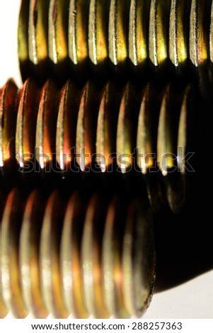 Three colorful steel bolts lying in parallel showing sharp grooves. Product photography. Industrial photography.
