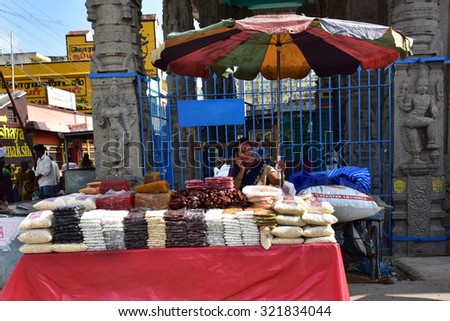 KANCHEEPURAM, TAMILNADU, INDIA, SEPTEMBER 21, 2015: Small-time seller of food items near Ekambaranatha temple in Tamil Nadu, talking on mobile phone. Sculpted pillar in the background.