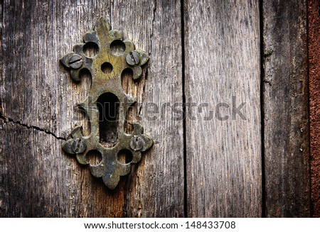 Keyhole in an old paneled wooden door; rusty and weathered. This image has been processed to make a more impactful, dramatic shot.