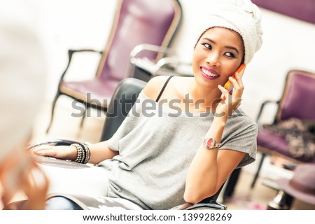 Young woman making a phone call while waiting at the hairdresser\'s.