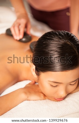 Asian woman enjoying a hot stone treatment.