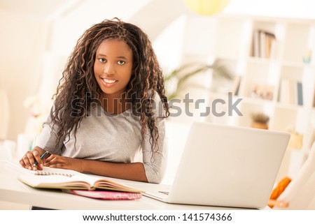 Portrait of an African-American teenage girl writing her homework.