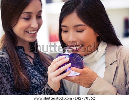 Two smiling women smelling the fragrance of different aromatherapy oils.