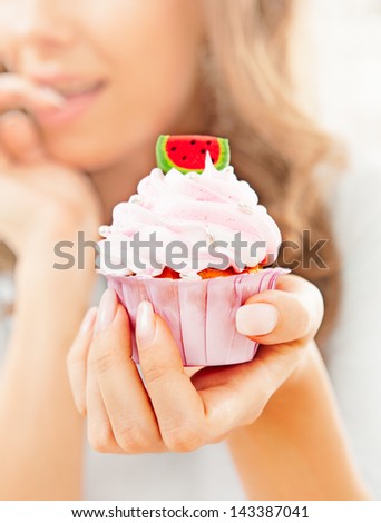 A woman holding a beautifully decorated delicious cupcake.