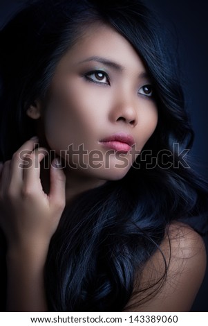 Young Asian woman with beautiful long hair gently touching her face.
