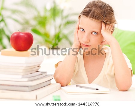 A cute schoolgirl sitting at home and worrying about her homework.