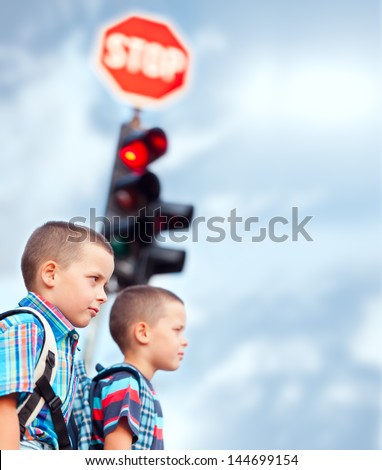 Two boys waiting to cross the street on their way to school.