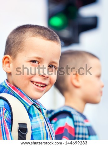 Two boys waiting to cross the street on their way to school.