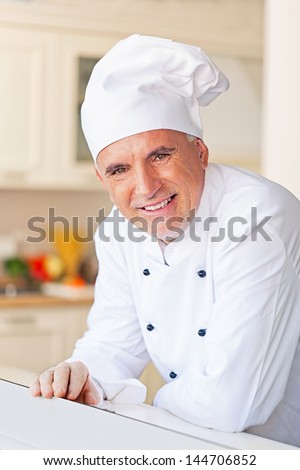 Smiling senior chef in his kitchen.