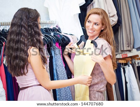 Two women at a boutique choosing a dress.
