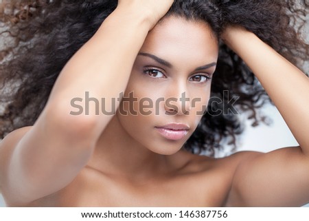 African woman posing with hands in hair.