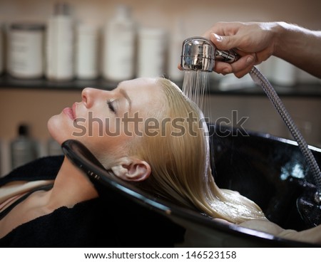 Smiling woman having her hair washed at the hairdresser\'s.