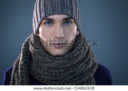 Handsome young man wearing a knit hat and a scarf.