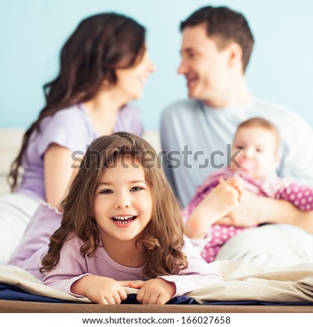 Happy family enjoying a weekend morning together in the bedroom.