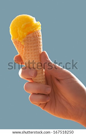 Female hand holding a lemon ice-cream cone.