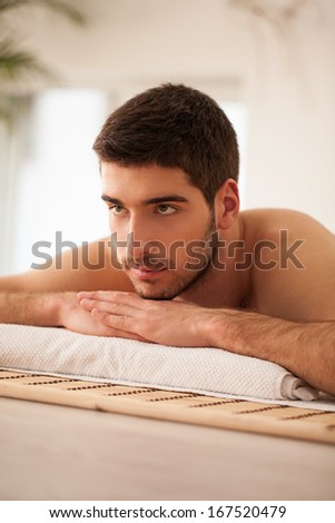 Young Caucasian man lying on the massage table and waiting for a massage.