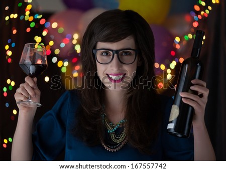 Portrait of a young woman with glasses holding a bottle and a glass of red wine.