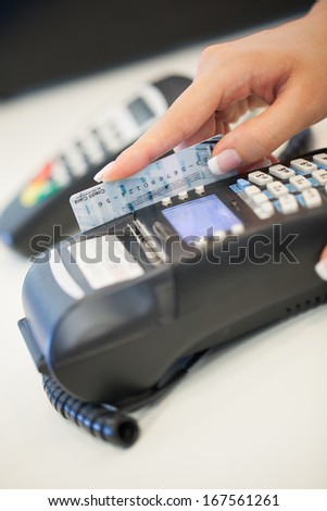 Female hand sliding a credit card through the card reader.