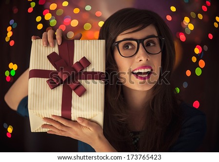 Hipster woman wondering what\'s in the gift-box she\'s holding.
