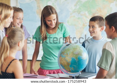 Group of primary schoolchildren around a globe in a geography lesson.