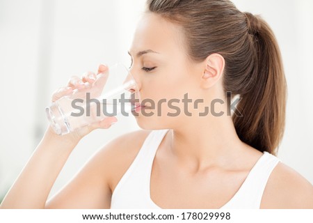 Studio shot of a young woman drinking a glass of water.