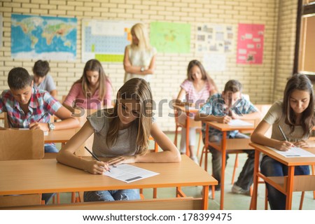 Primary School Students Being Monitored By Their Teacher While Doing A Test.