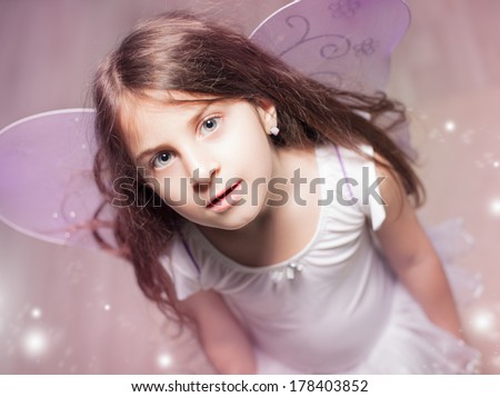 Cute Caucasian girl with purple fairy wings.