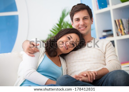Happy young Caucasian couple posing together at home.