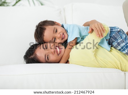 Smiling mother hugging her son tightly.