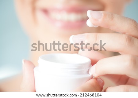 Hands of a woman about to apply face cream.
