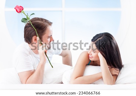 Smiling man giving a rose to his girlfriend on Valentine\'s Day morning.