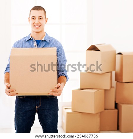 Smiling Caucasian man carrying a cardboard box while moving out.