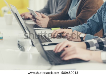Hands of group of unrecognisable cropped young people typing on laptop.
