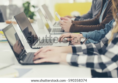 Hands of group of unrecognisable cropped young people typing on laptop.