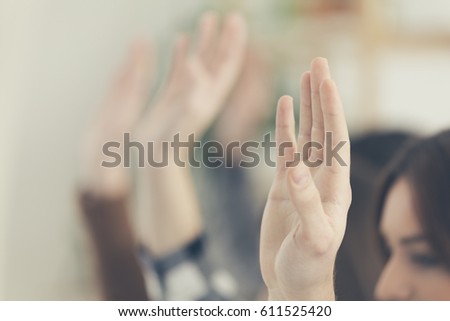 Students raising hands in classroom.