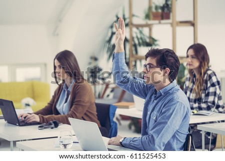 College students raising hands in classroom