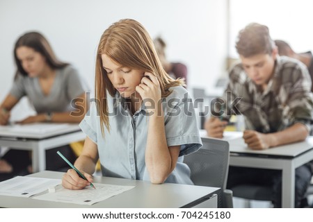 Pretty Caucasian girl high school student doing exam at classroom.